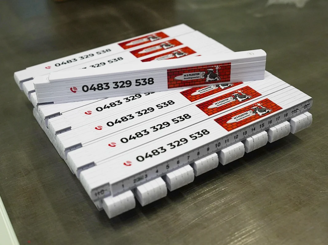 Miary składane z nadrukiem telefonu. Produkcja miar reklamowych z logo branży budowlanej, gadżety firmowe.