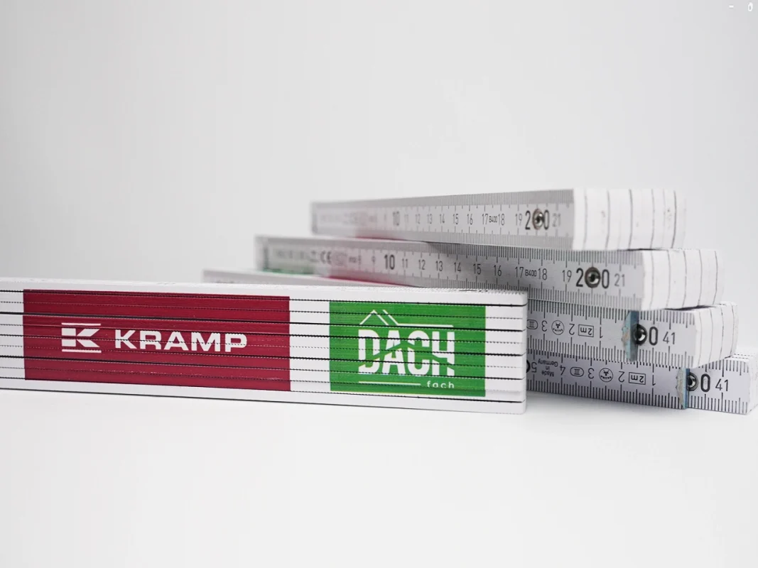 Miary składane z logo Kramp i Dach Fach. Produkcja personalizowanych miar reklamowych, gadżety firmowe.