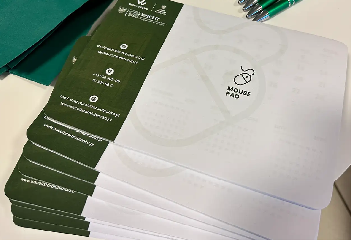 Stos mousepadów reklamowych WSCEIT. Podkładki pod mysz z logo i danymi kontaktowymi, produkcja gadżetów.