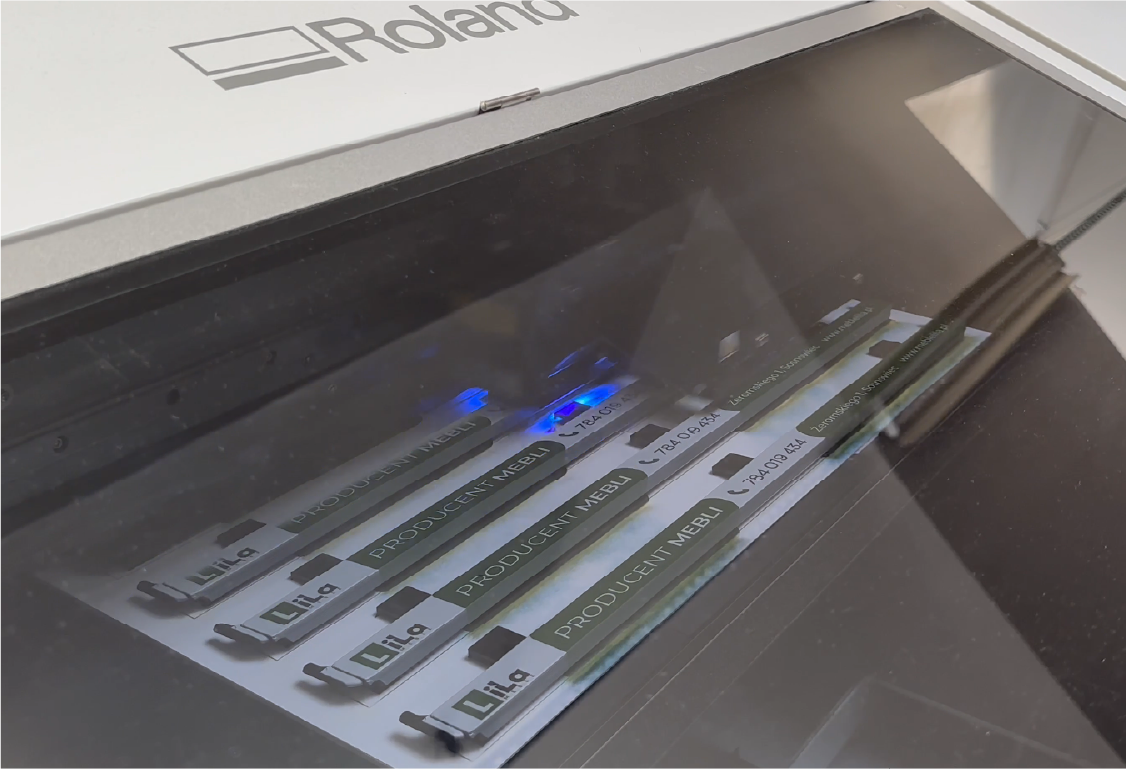 Druk ramek tablic rejestracyjnych. Produkcja ramek reklamowych dla producenta mebli Lila na maszynie Roland.