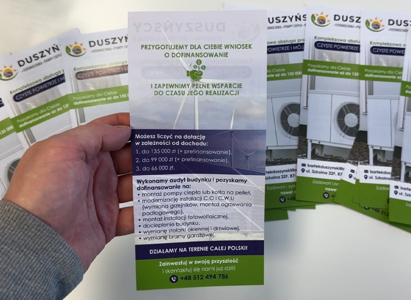 Ulotka reklamowa trzymana w ręce, biało-zielona z nadrukiem. Ulotki dofinansowanie.