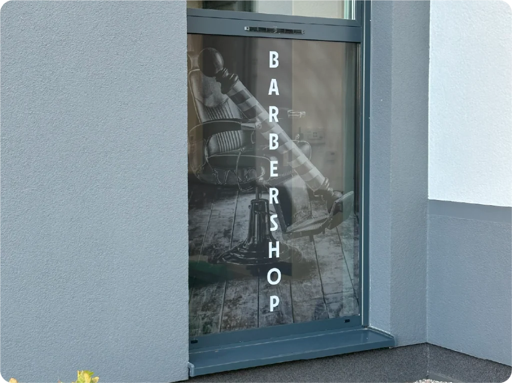 Oklejanie witryny barbershopu folią One Way Vision. Grafika na szybach, reklama na oknach salonu.