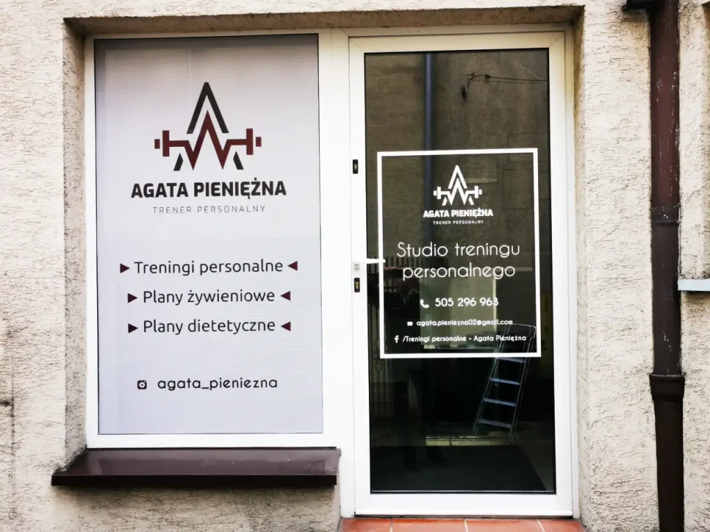 Oklejanie witryny studia treningu folią OWV. Reklama na szybach z ofertą personalnych planów treningowych.